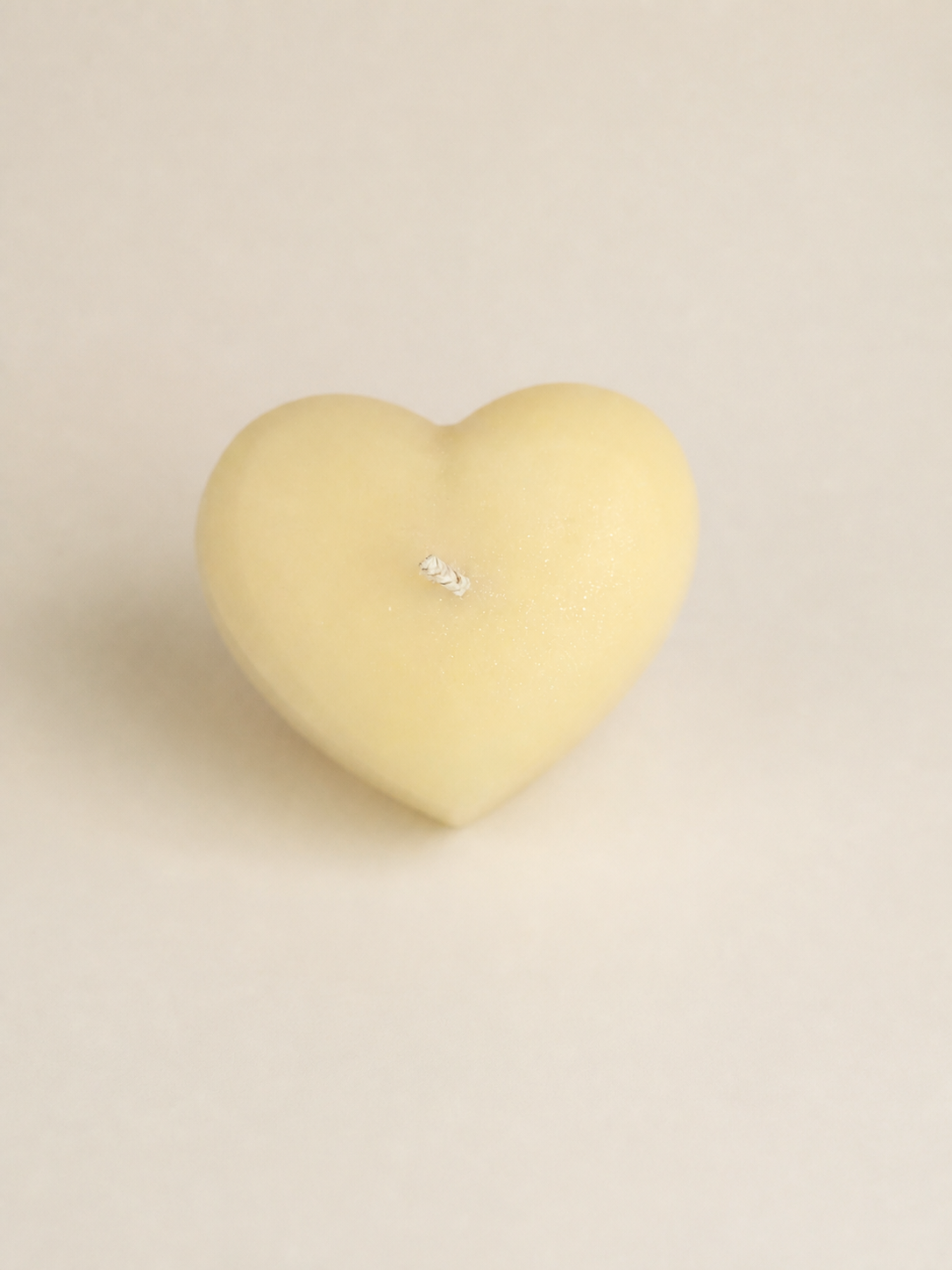 Heart-shaped sculptural candle in a soft neutral presentation