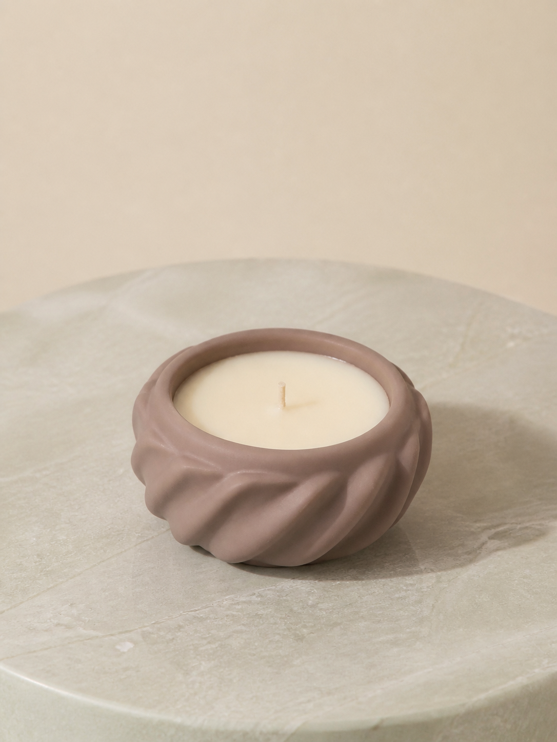 Ivory wax candle poured into a taupe pleated sculptural vessel