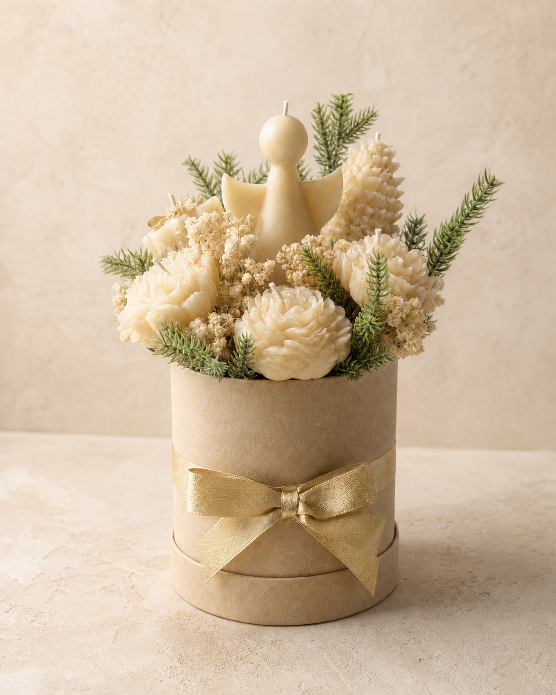 Ivory angel candle surrounded by sculptural flowers, evergreen foliage and a gold ribbon
