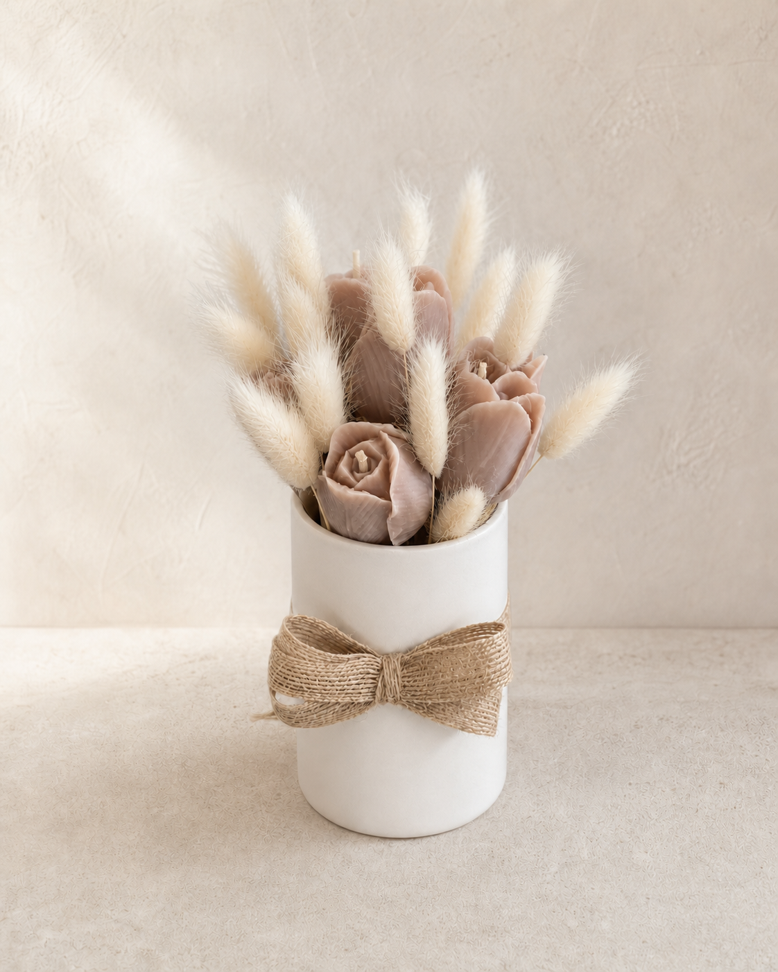 Taupe sculptural tulip candles and ivory bunny tails in a white vase with natural ribbon