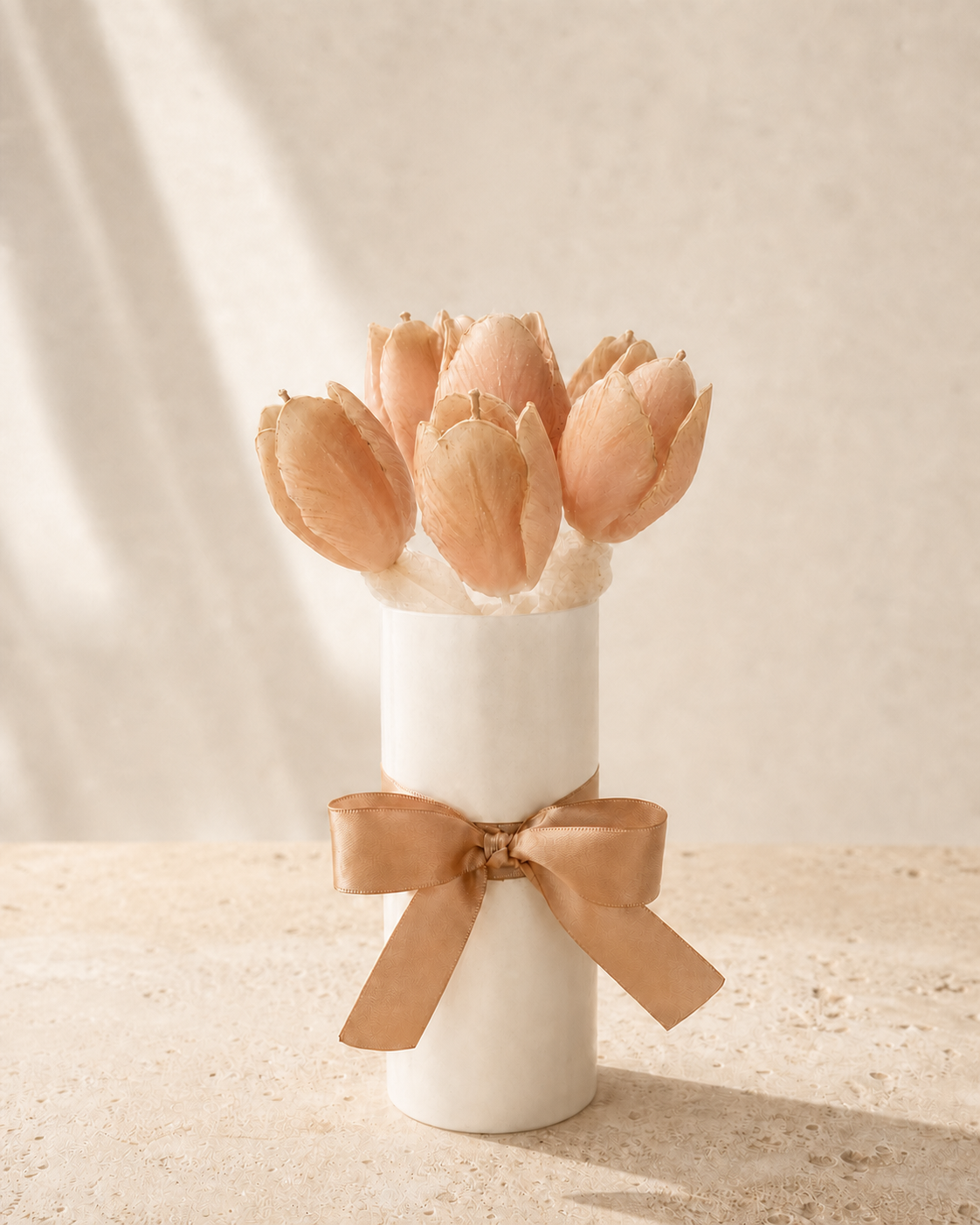 Blush tulip candle bouquet in a white vase with a satin bow