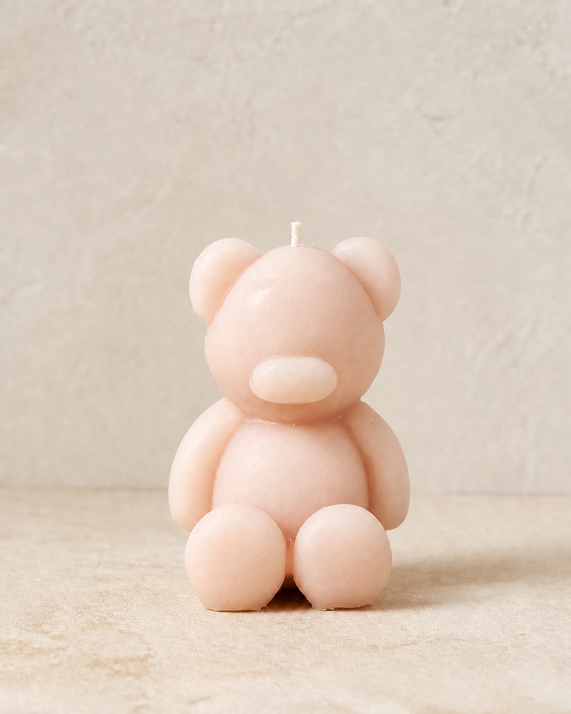 Minimal blush sculptural teddy bear candle in warm directional light