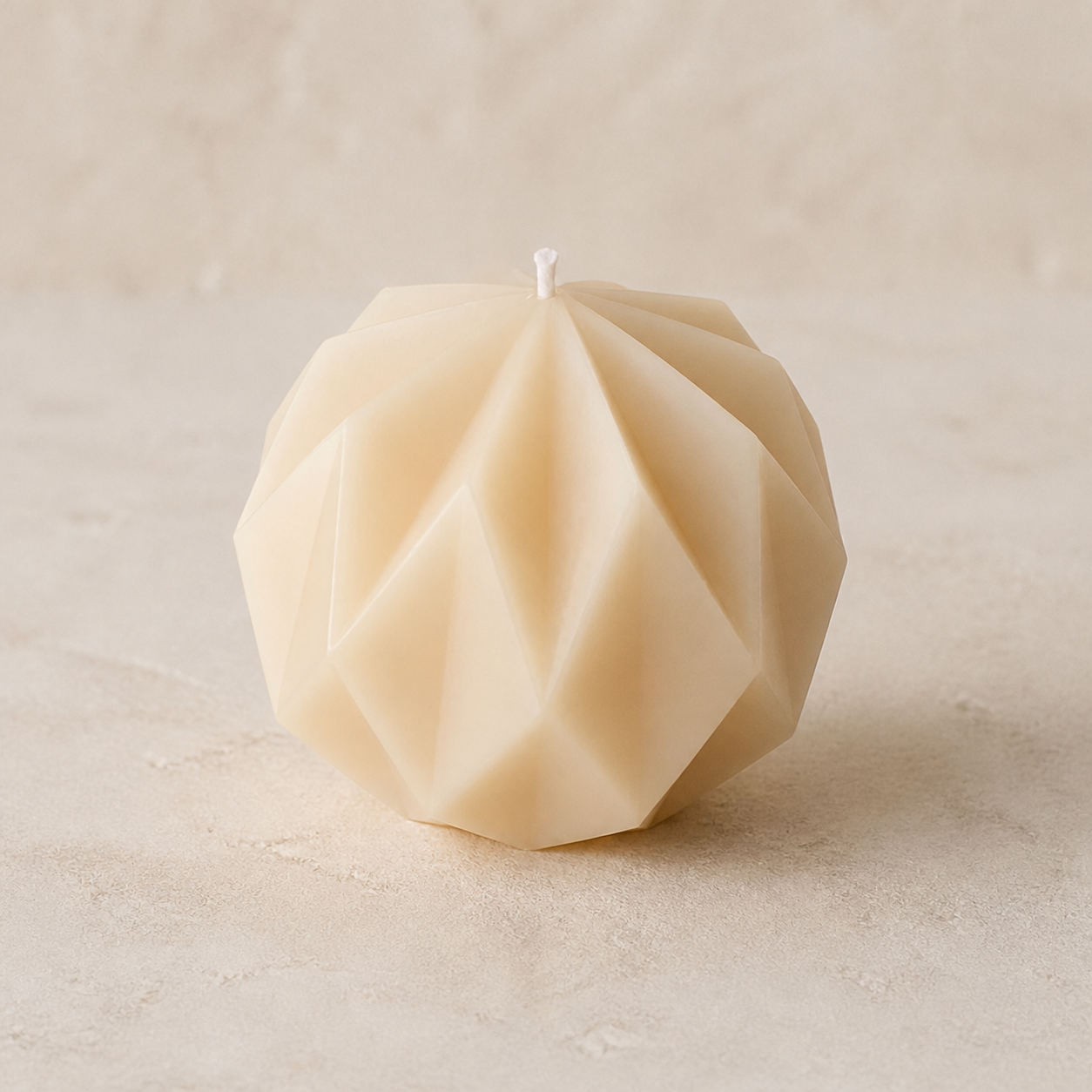 Ivory round sculptural candle with crisp geometric facets