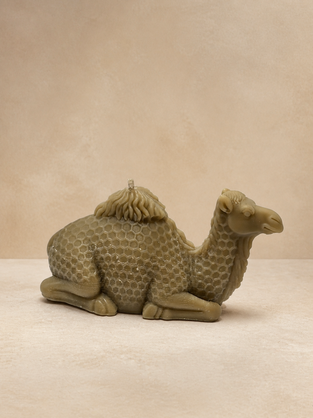 Taupe camel sculptural candle with honeycomb detailing in a warm desert-inspired studio setting